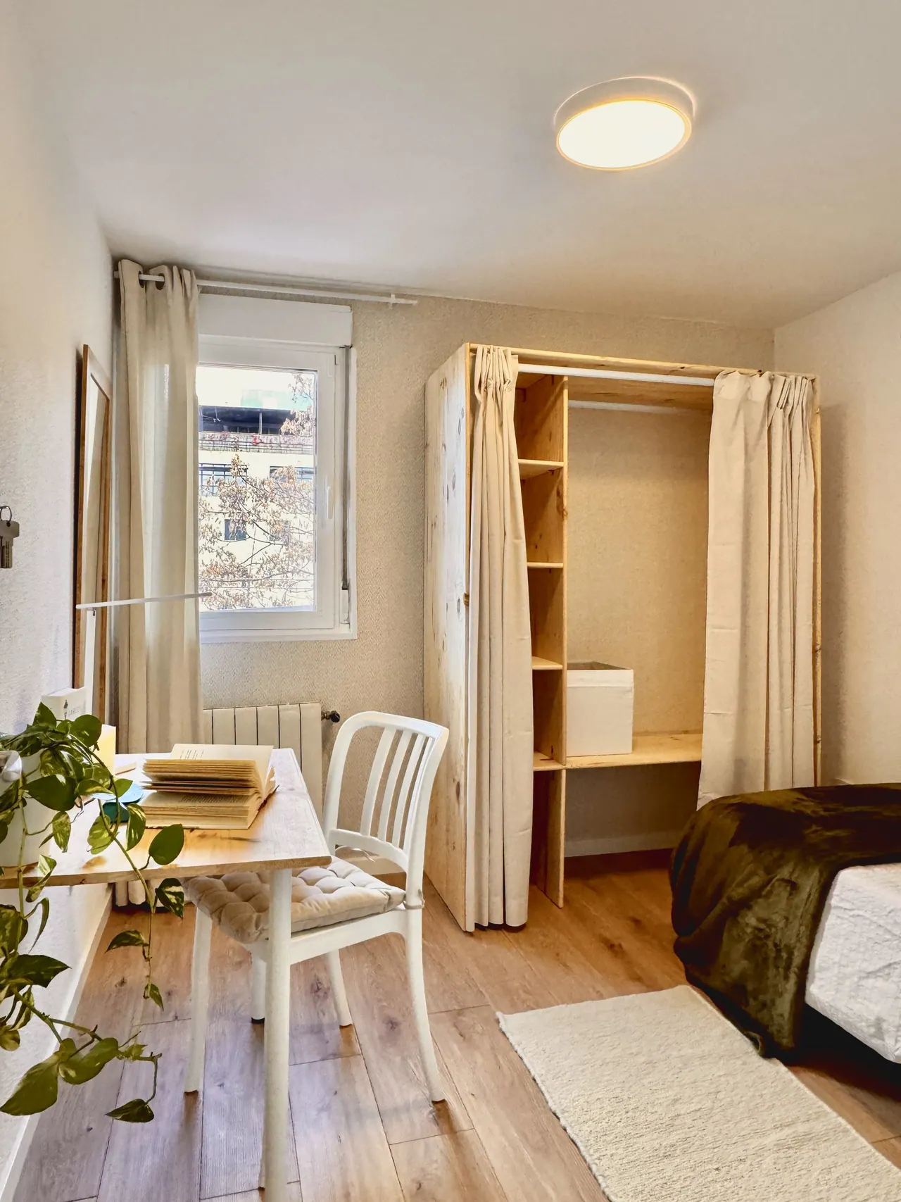 Habitación con escritorio, silla blanca, armario abierto de madera y ventana (foto 5 de 7)