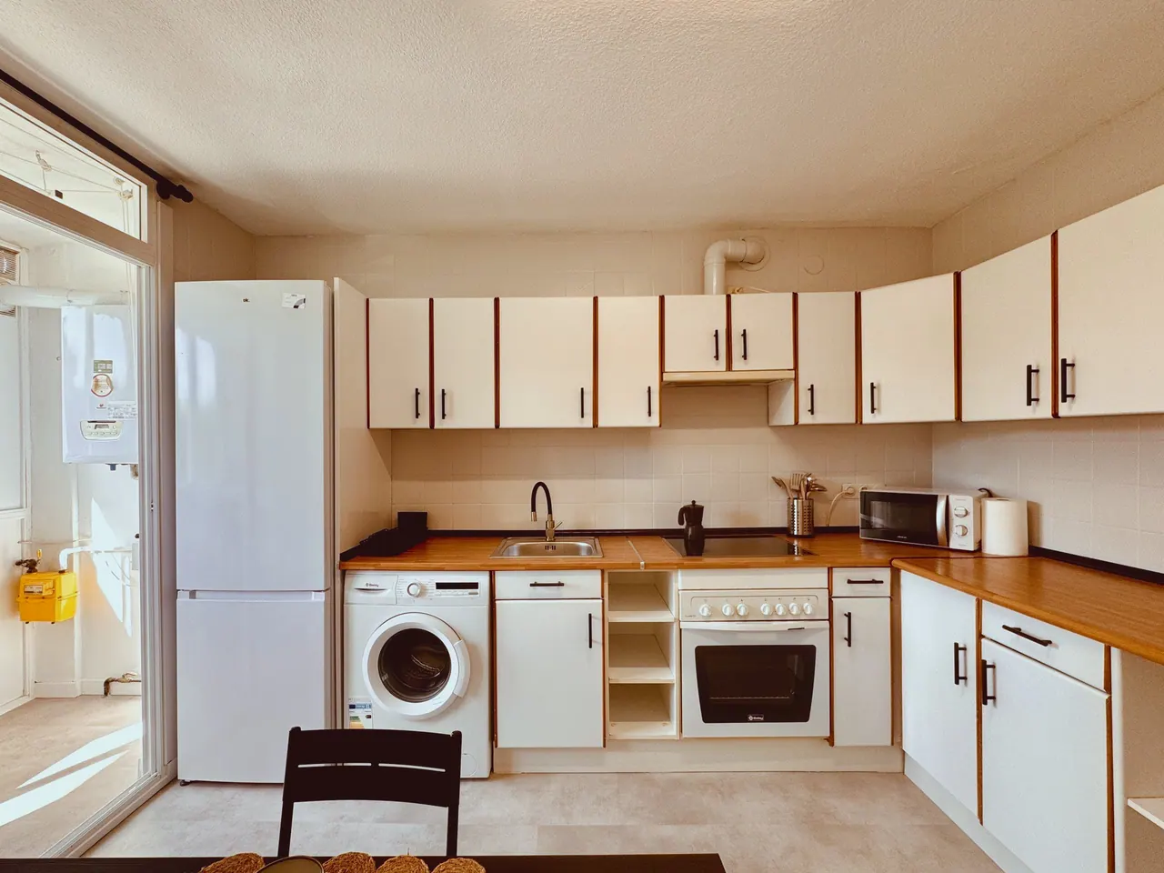 Cocina con frigorífico, lavadora, horno y muebles blancos con tiradores negros (foto 2 de 9)