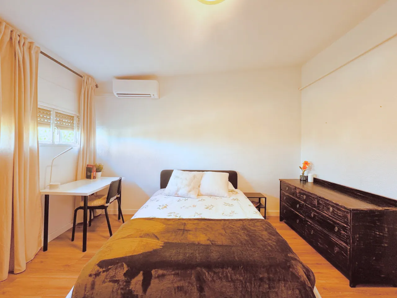 Habitación con cama de matrimonio, cómoda negra, escritorio junto a la ventana y aire acondicionado (foto 7 de 9)