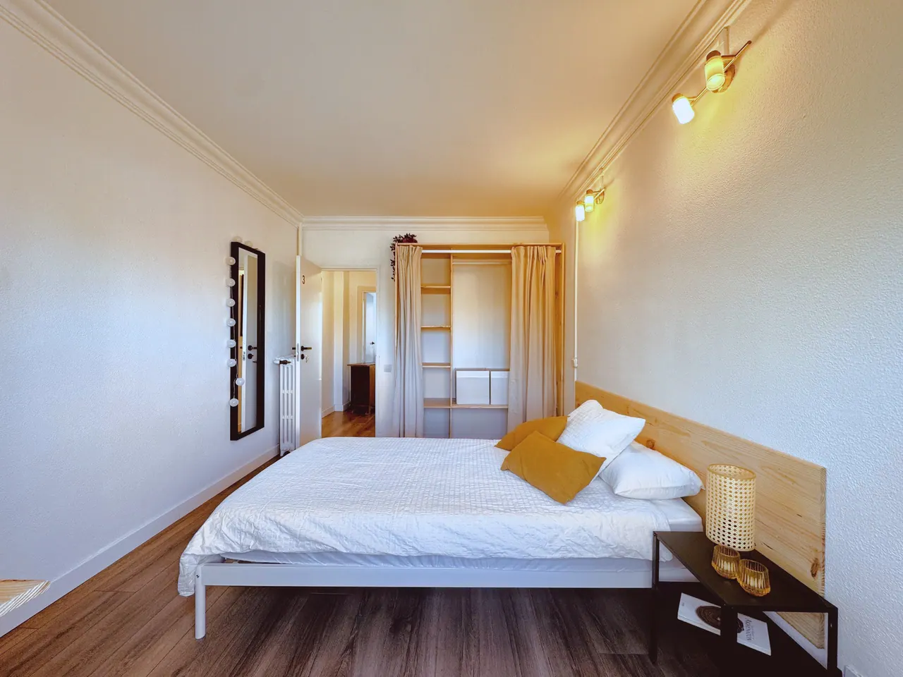 Habitación con cama de matrimonio, cabecero de madera, apliques de luz y armario abierto (foto 8 de 9)