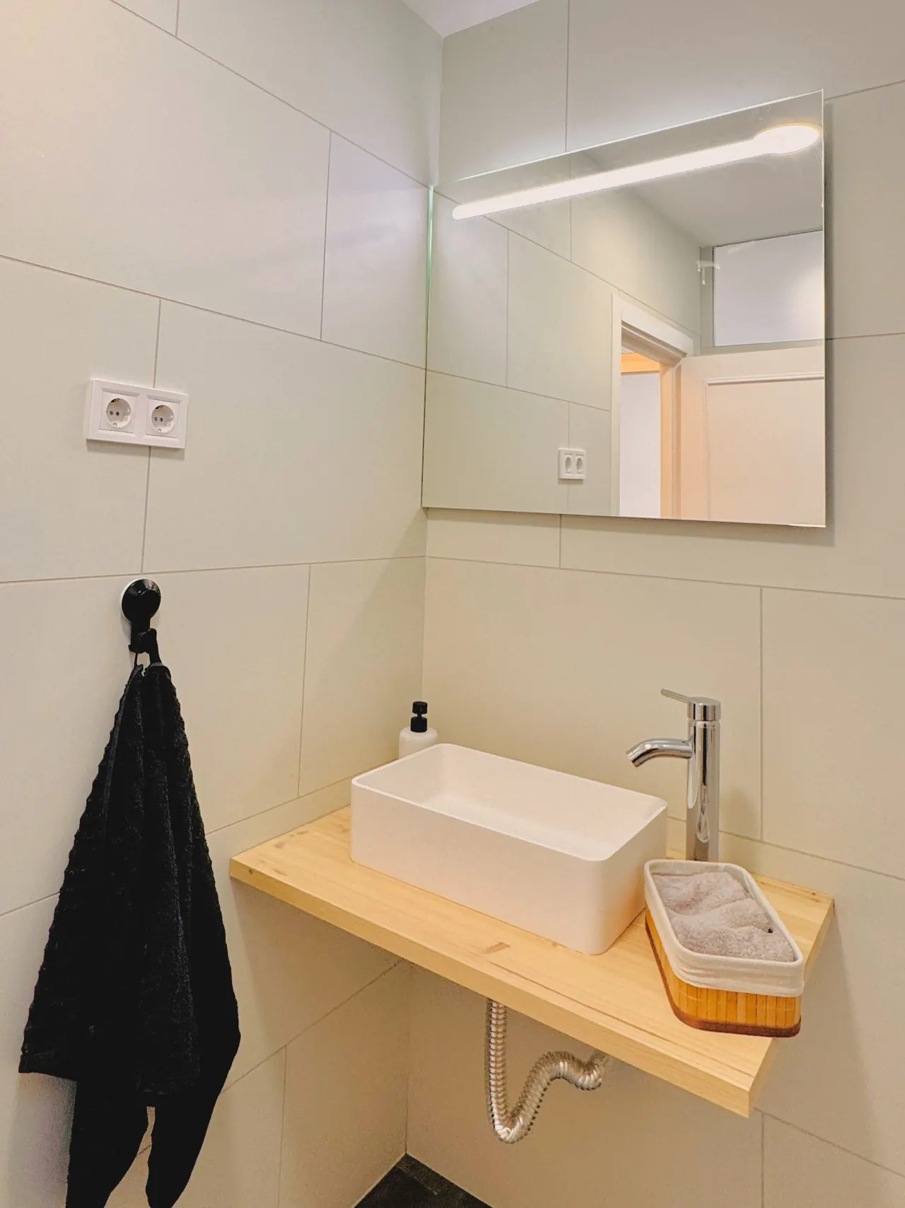 Lavabo blanco sobre encimera de madera con espejo iluminado (foto 2 de 7)