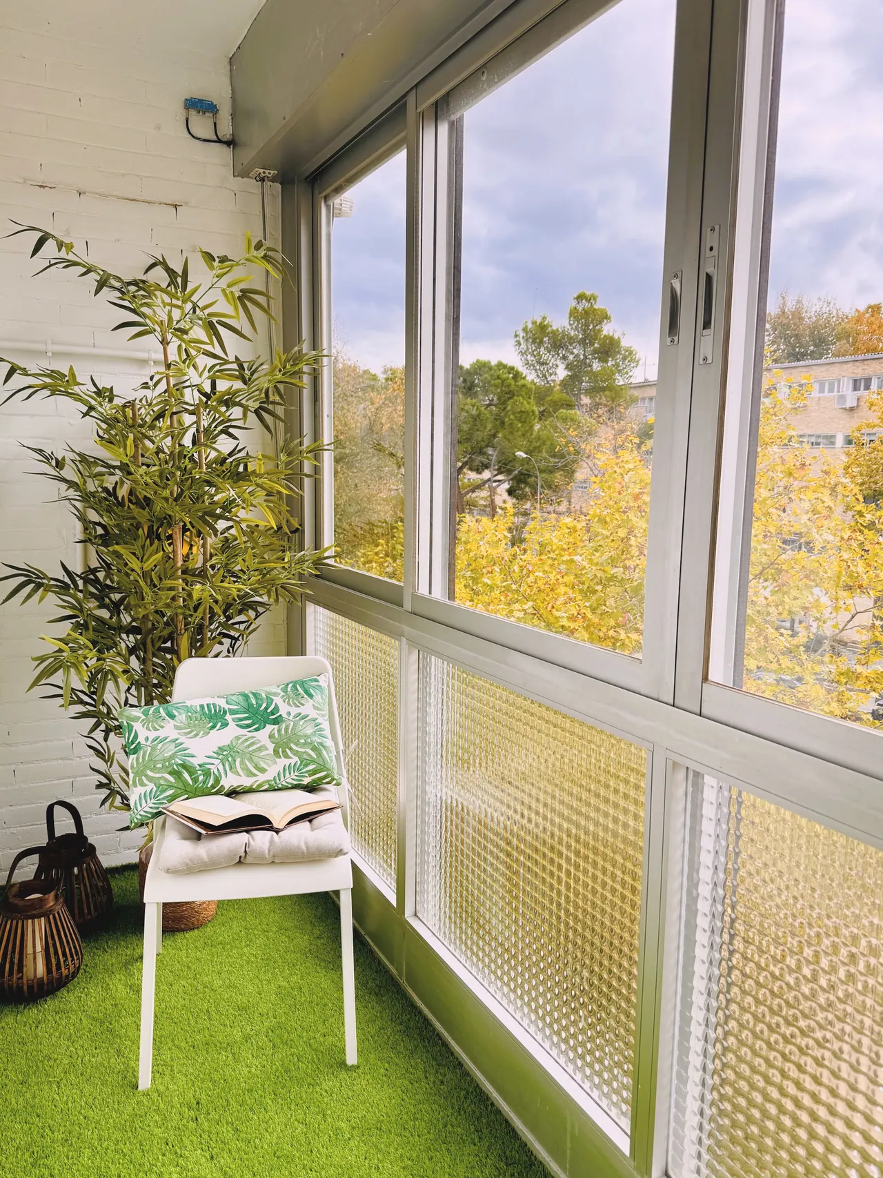 Terraza acristalada con césped artificial, silla blanca y plantas (foto 3 de 7)