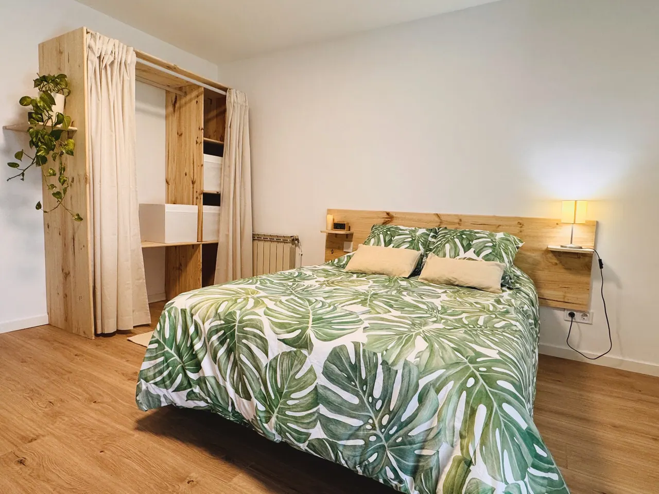 Habitación con cama de matrimonio, funda de hojas verdes y armario abierto de madera con cortina (foto 4 de 7)