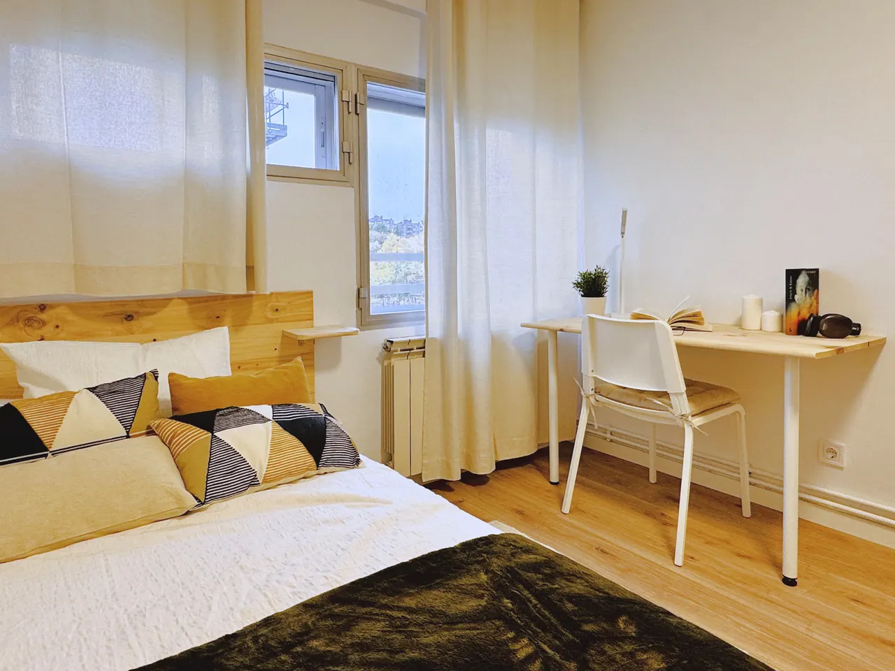 Habitación con cama, escritorio blanco y ventana con cortinas claras (foto 5 de 7)