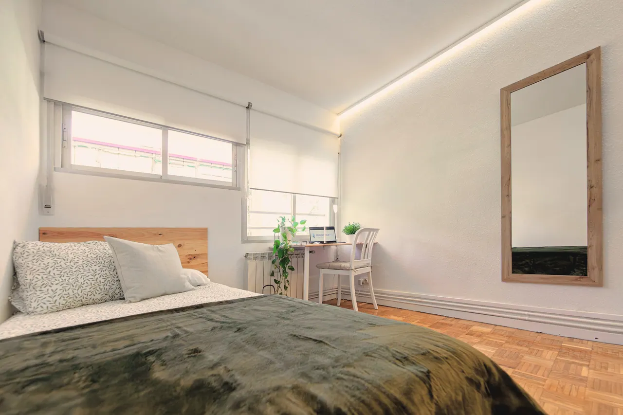 Habitación con cama de matrimonio, escritorio bajo la ventana y espejo de madera (foto 6 de 7)
