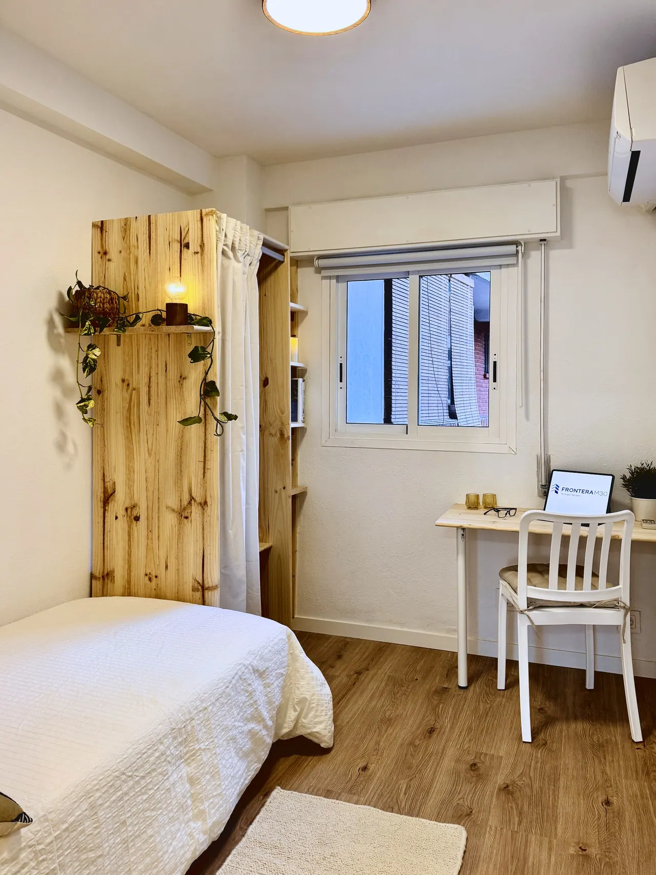 Habitación con cama individual, escritorio bajo la ventana y estantería de madera con plantas (foto 6 de 7)