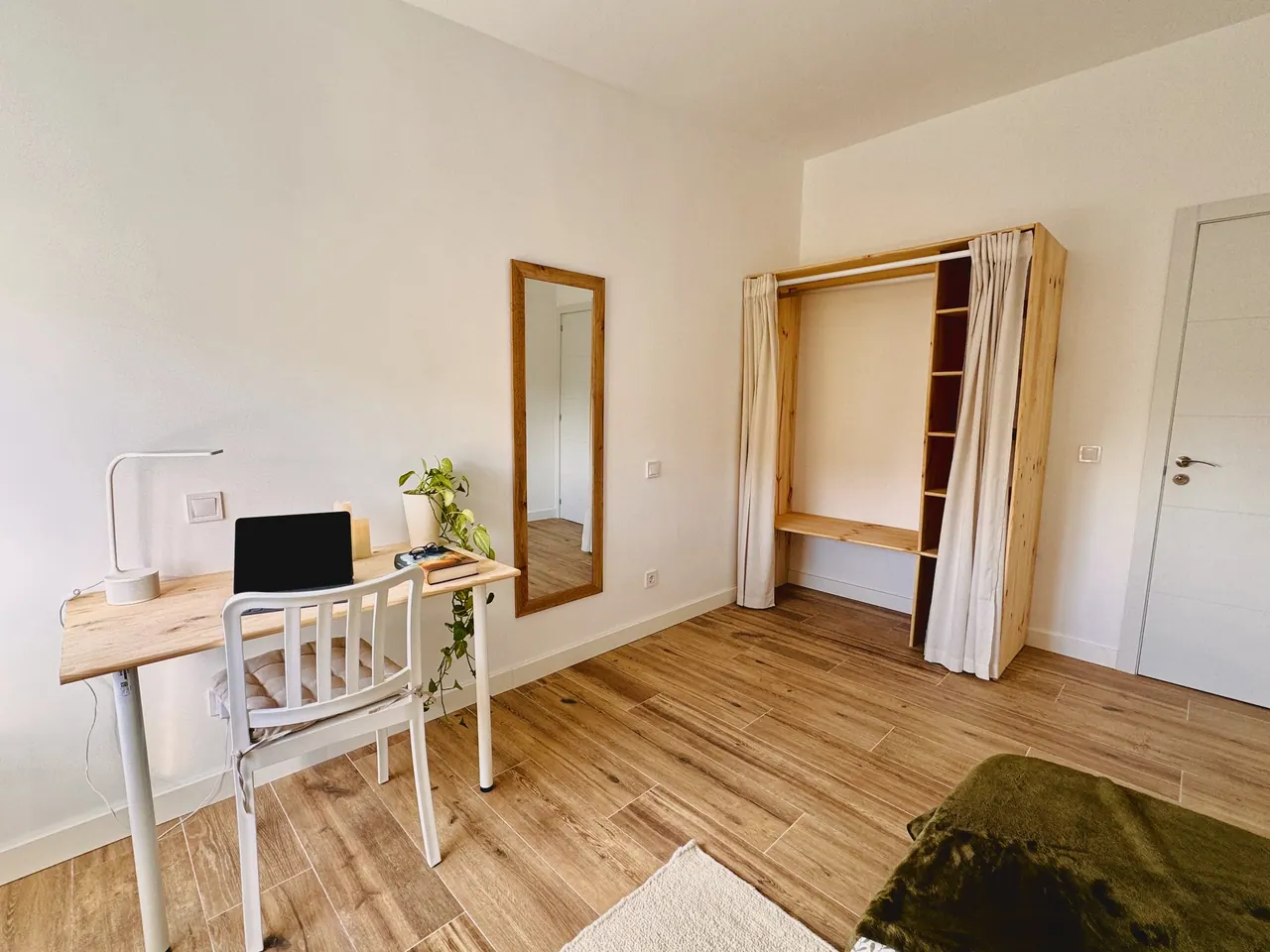 Habitación con escritorio de madera, espejo y armario abierto con cortina (foto 7 de 8)