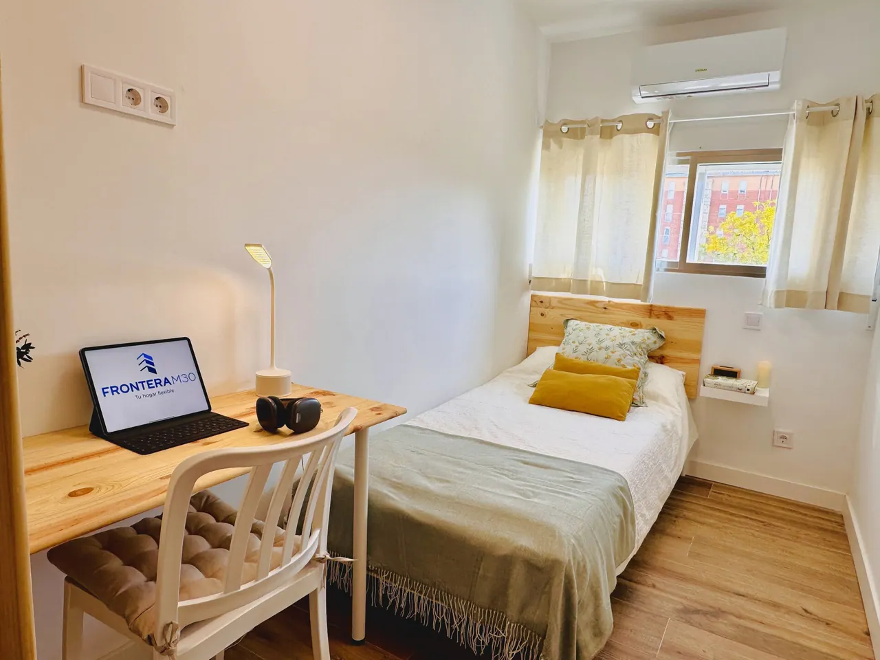 Habitación con cama individual, escritorio de madera con portátil y aire acondicionado (foto 8 de 8)
