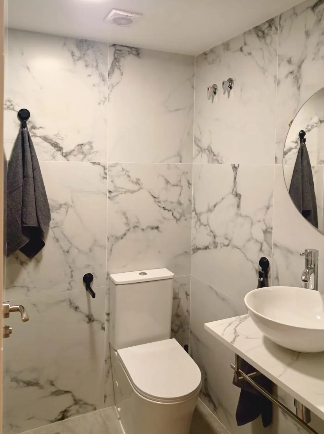 Segundo baño de cerámica blanca con inodoro, lavabo sobre repisa y toallero (foto 5 de 8)