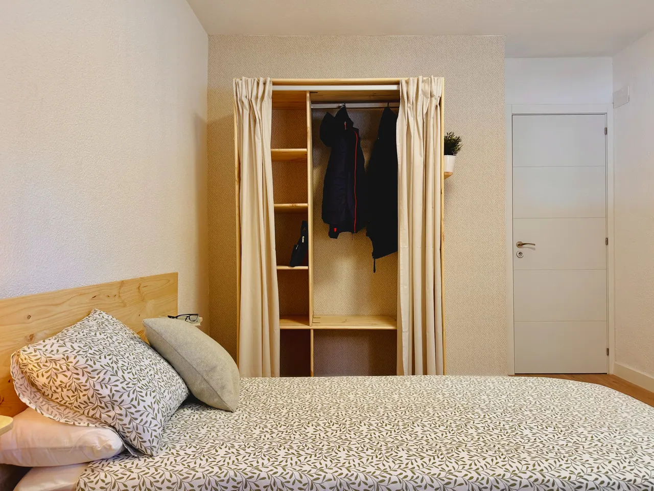 Habitación con cama de matrimonio y armario abierto de madera con cortinas (foto 7 de 8)