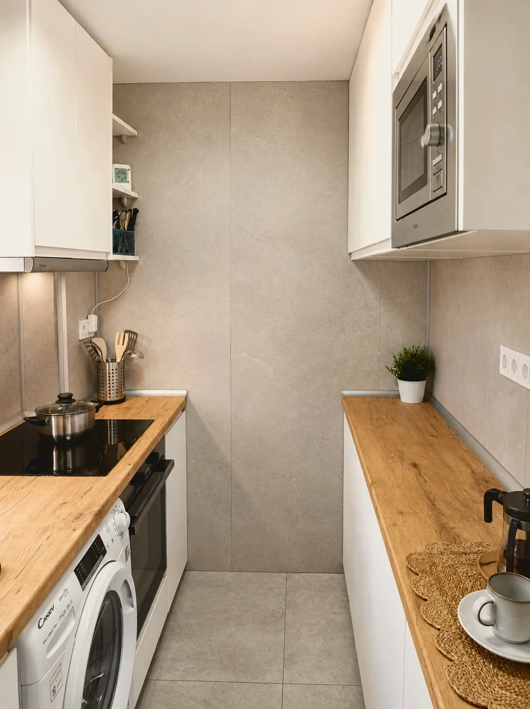 Cocina blanca con encimera de madera, lavadora, placa y microondas (foto 2 de 8)