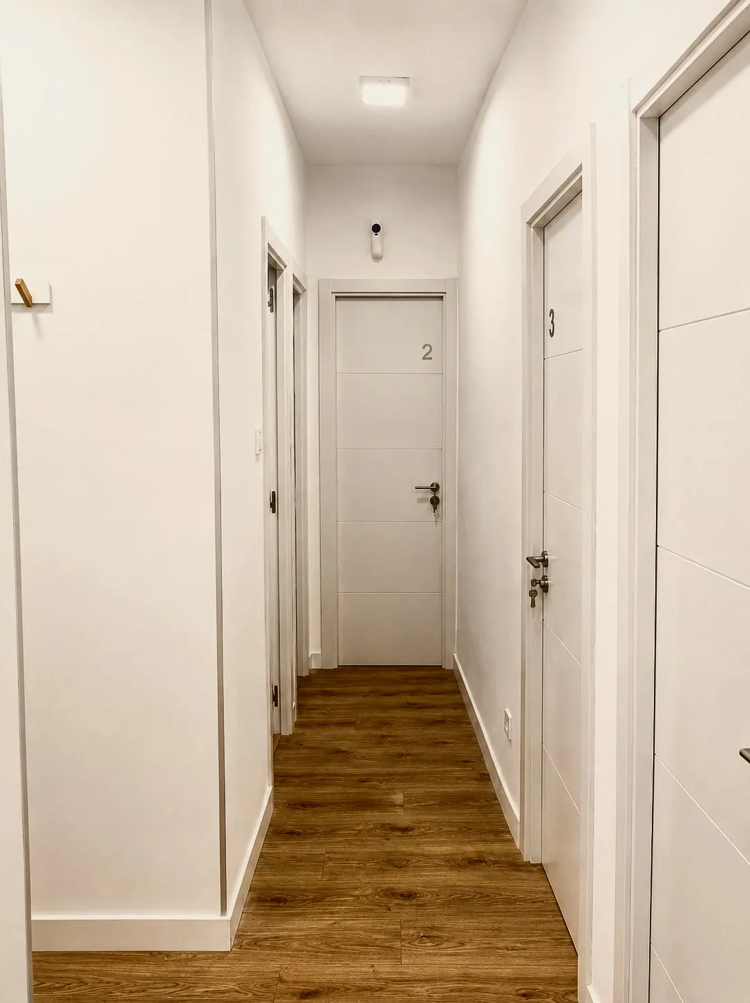 Pasillo blanco con suelo de madera y puertas a las habitaciones (foto 5 de 8)